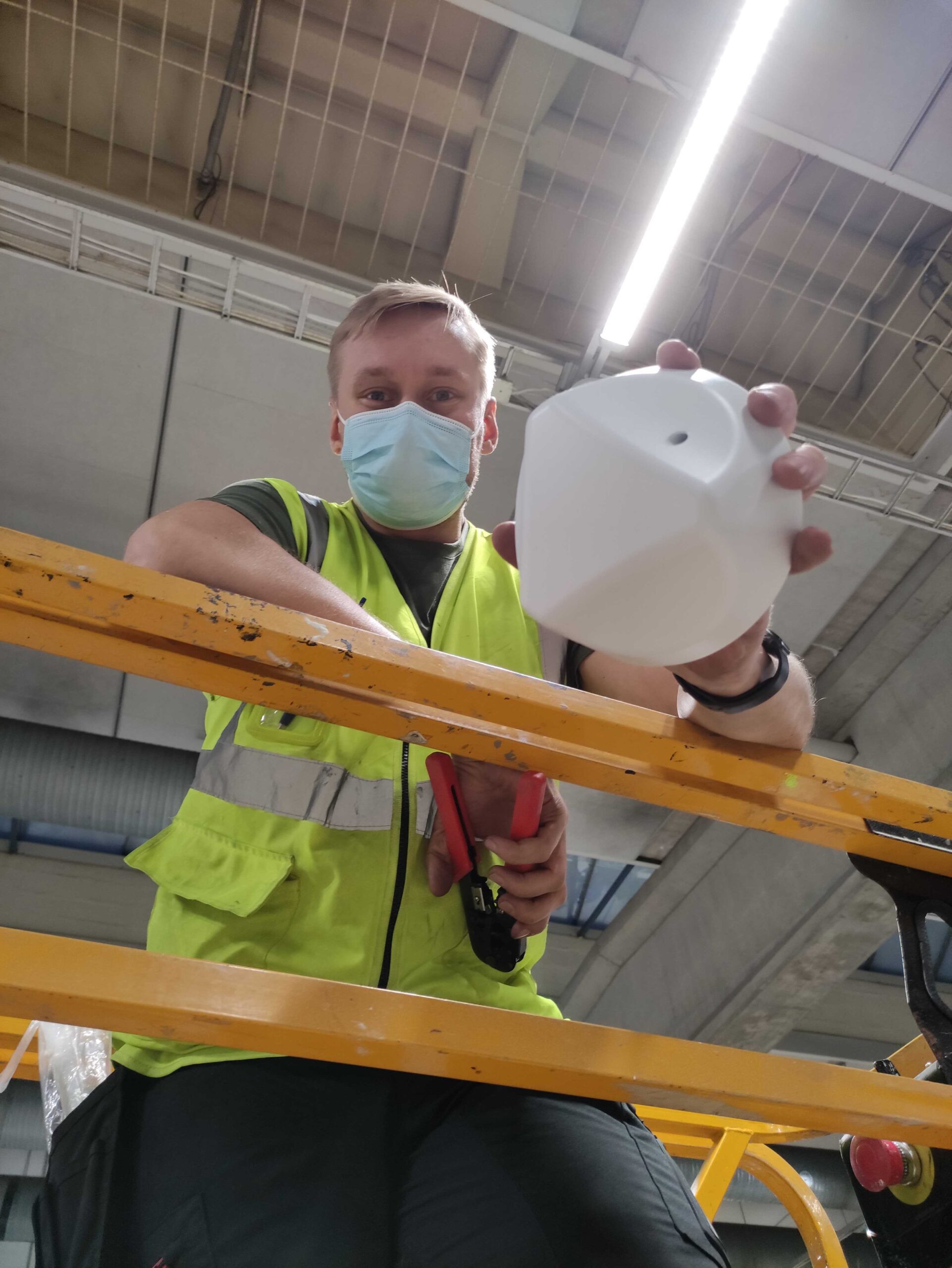 uwb-modern-industrial-iot. UWB anchors being installed by a guy on a lifting machine to the roof of a factory.